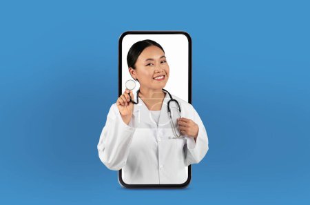 Cette image montre une jeune femme asiatique médecin sur un écran de smartphone, offrant des services de télésanté innovants à partir d'un bureau soigné et professionnel.