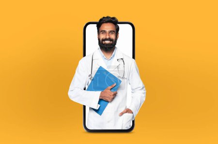 A young indian man doctor stands inside the screen of a smartphone, symbolizing a virtual consultation, set in a modern, light-filled clinic.
