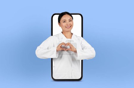 Asian lady physician offers remote consultation, visible on a smartphone screen, surrounded by soft lighting, showing heart gesture