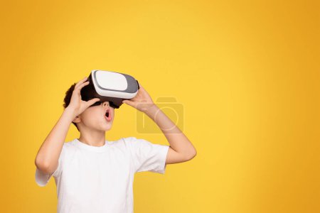 Téléchargez les photos : Un jeune garçon portant un t-shirt blanc tenant un globe virtuel noir et blanc dans ses mains. - en image libre de droit