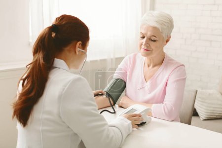 Eine Ärztin hört der Seniorin aufmerksam mit einem Stethoskop zu. Der Zuhörer wirkt konzentriert und engagiert, während die andere Dame ihren Herzschlag oder Atem kontrollieren zu lassen scheint..