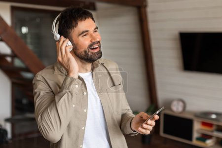 Un homme qui porte un casque écoute de la musique, immergé dans le son. Il semble concentré et engagé comme il aime ses airs préférés.