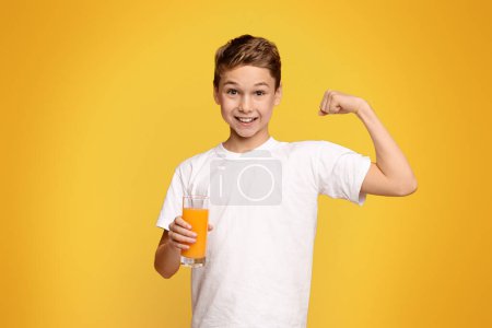 Photo for A young boy holding a glass filled with orange juice. - Royalty Free Image