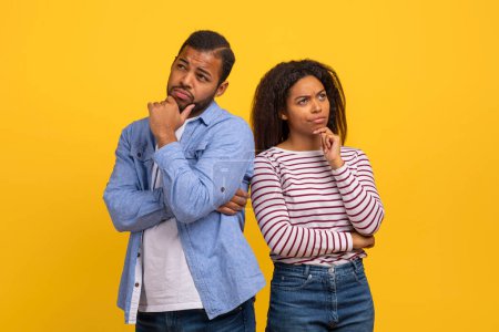 Photo for A young African American man and woman stand with their backs to each other, both appearing thoughtful and concerned. - Royalty Free Image