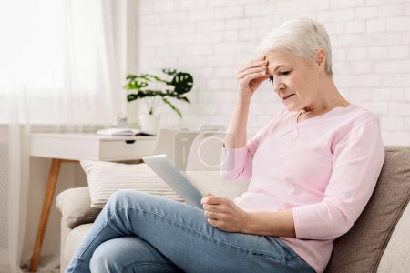 Téléchargez les photos : Femme âgée confondue utilisant un ordinateur tablette, regardant déçu, ne comprend pas les gadgets modernes, espace vide - en image libre de droit
