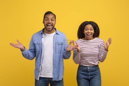Photo for A cheerful African American man and woman stand next to each other, both with arms outstretched and mouths wide open in a display of excited surprise - Royalty Free Image