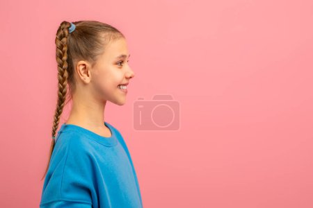A young girl with a neatly braided hairdo is featured in this portrait. Her braid is prominently displayed, adding a touch of elegance to her appearance, looking at copy space