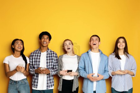 Foto de Un momento alegre compartido entre un grupo multiétnico de adolescentes, todos mirando hacia arriba y riendo con genuina felicidad. - Imagen libre de derechos