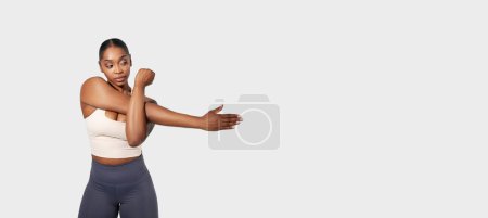 Foto de Mujer afroamericana en la imagen está flexionando su brazo, mostrando su definición muscular. El fondo es blanco liso, enfatizando el enfoque en su brazo flexionado, panorama, espacio de copia - Imagen libre de derechos