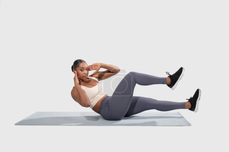 Mujer afroamericana está participando activamente en una rutina de ejercicios en una estera. Ella está enfocada y demostrando la forma adecuada mientras completa varios movimientos para mejorar la fuerza y la flexibilidad.