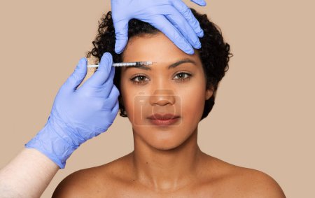 Eine Frau bekommt eine Füllstoffspritze auf die Stirn. Ein medizinisches Fachpersonal verabreicht die Injektion sorgfältig, um Falten und feine Linien zu reduzieren, Nahaufnahme