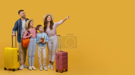 Foto de Una familia feliz que consiste en un padre, una madre, un hijo y una hija con sus coloridas maletas, preparados para embarcarse en unas vacaciones, apuntando al espacio de copia - Imagen libre de derechos