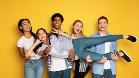 Photo for A diverse group of teenagers is seen gathering together and striking various poses in front of a camera, creating a lively and engaging atmosphere, holding their friend - Royalty Free Image