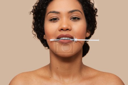 Halbnackte Frau wird mit einer Spritze zwischen den Lippen gezeigt. Sie scheint sich auf eine Injektion vorzubereiten oder Medikamente oral einzunehmen.