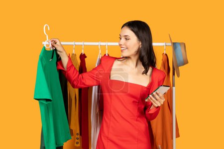 Une femme se tient devant un porte-vêtements, parcourant les différents objets. Elle semble concentrée et déterminée à trouver quelque chose qui attire son attention.