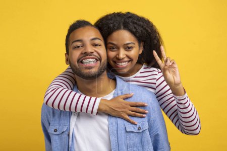 Afroamerikaner und Afroamerikanerinnen umarmen sich fest, mit einem breiten Lächeln im Gesicht. Beide scheinen wirklich glücklich und zufrieden in den Armen zu liegen.