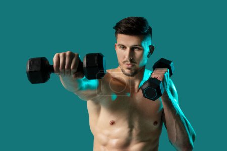 A shirtless man is shown standing on a green background while holding dumbbells in each hand. He appears focused and determined as he performs weightlifting exercises.