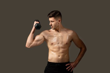 Ein Mann ohne Hemd ist zu sehen, wie er in einem Fitnessstudio eine Hantel hält. Er wirkt fokussiert und engagiert in seiner Trainingsroutine, zeigt Stärke und Entschlossenheit.