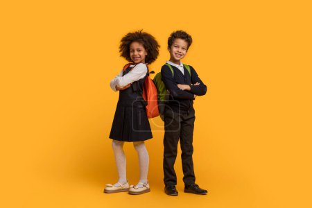 Dos niños afroamericanos vestidos con uniformes escolares están parados sobre un fondo amarillo brillante. Parecen estar esperando en fila, con los ojos enfocados hacia adelante.