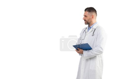 Un médico hombre, vestido con una bata blanca de laboratorio y sosteniendo un portapapeles azul, se pone de pie sobre un fondo blanco llano. Aparece enfocado y profesional, listo para sus deberes médicos, espacio de copia