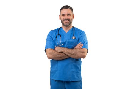 Ein Mann mit blauem Peeling und einem Stethoskop um den Hals steht mit verschränkten Armen in professioneller Pose. Er strahlt Zuversicht und Fachkompetenz in einem medizinischen Umfeld aus.