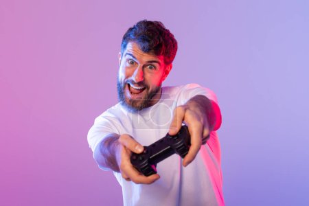 A man holds a video game controller, his fingers pressing buttons and moving joysticks as he plays a game in neon light