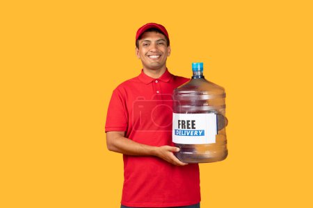 Delivery man is holding a large bottle filled with water. He has a strong grip on the bottle and is standing upright, doing delivery service, yellow background