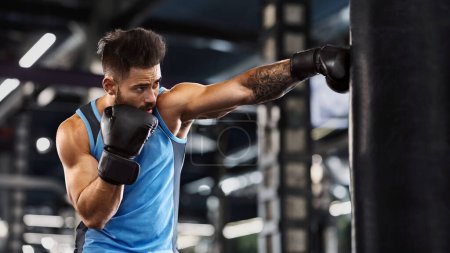 Junger Sportler boxt im Fitnessstudio, Typ Boxsack, freier Platz