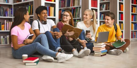 Hora de descansar. Grupo de amigos adolescentes internacionales riendo mientras se preparan para los exámenes escolares, biblioteca interior

