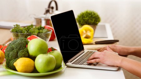 Blogger de alimentos escribiendo un nuevo post, fruta cerca de la computadora portátil con pantalla en blanco