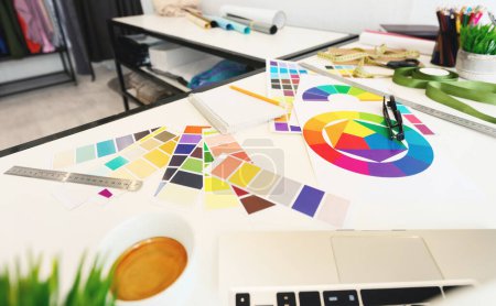 A vibrant and organized workspace is captured here, featuring an array of color swatches spread out alongside a color wheel, suggesting color scheme planning. Various design tools