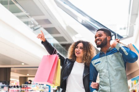 Gran concepto de venta. Jóvenes afroamericanos pareja haciendo compras juntos en el centro comercial de la ciudad, panorama

