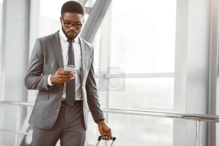 Geschäftsmann SMS auf Smartphone zu Fuß in Flughafen-Terminal, freier Platz