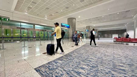 Photo for DUBAI, UNITED ARAB EMIRATES.15 SEPTEMBER 2023. Man with luggage, walking in Dubai Airport, checking flight info board - Royalty Free Image