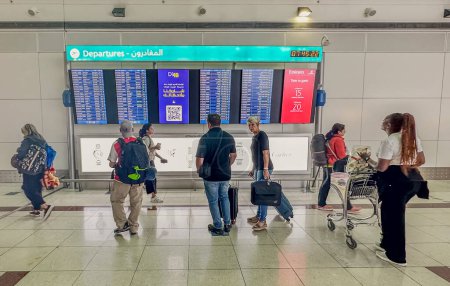 Photo for DUBAI,UAE. 16 SEPTEMBER 2023. Traveler stands in the bustling airport, studying the departure information board with focused anticipation for the imminent journey ahead - Royalty Free Image
