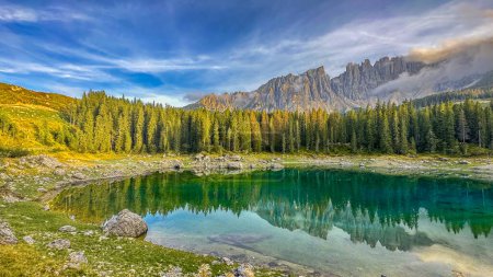 Photo for Lago di Carezza,Graceful at 1,519m, an alpine gem with emerald waters, cradled by spruce trees, framed by the majestic Dolomites,a fairy tale woven in nature's scenic tapestry - Royalty Free Image