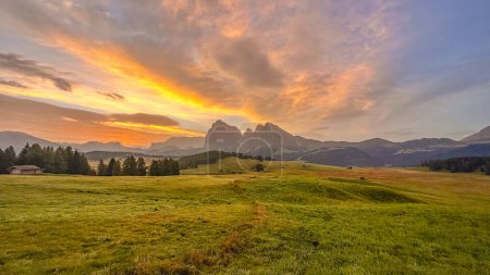 Photo for Alpe di Siusi,Europe's largest alpine pasture in South Tyrol, Italy. At sunrise, Dolomites' enchantment unfolds,meadows, mountains, hay huts,a rolling sea of green waves - Royalty Free Image