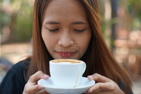Photo for Asian woman inhaling aromatic coffee - Royalty Free Image