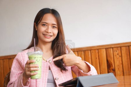 Photo for Asian woman braces watch computer Drink green tea to refresh. - Royalty Free Image