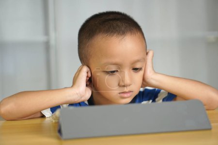 Foto de El chico se cubrió los oídos porque no quería oír los sonidos aterradores que provenían de la computadora.. - Imagen libre de derechos
