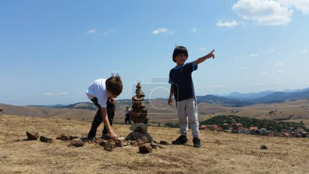 Téléchargez les photos : Des enfants heureux jouant sur le terrain vert, le jour ensoleillé. Garçons Summer photo. Paysage montagne - en image libre de droit