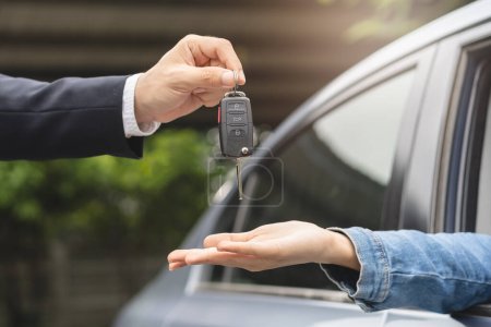 Photo for Transportation rental automotive business concept. Close up hands of rental auto agent giving car remote key to client to travel sightseeing. - Royalty Free Image