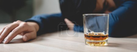 Foto de Drunk man fall asleep on the table with whiskey glass - Imagen libre de derechos