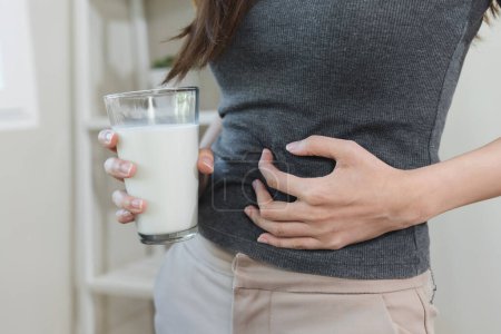 Téléchargez les photos : Lactose intolerance concept. Woman pushing glass of milk deny to drink. - en image libre de droit