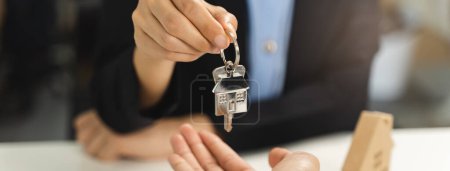 Téléchargez les photos : Agent immobilier donnant une clé d'appartement au nouveau propriétaire après la signature du contrat de location. - en image libre de droit
