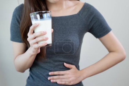 Foto de Concepto de intolerancia a la lactosa. Mujer con dolor de estómago porque bebe leche. - Imagen libre de derechos