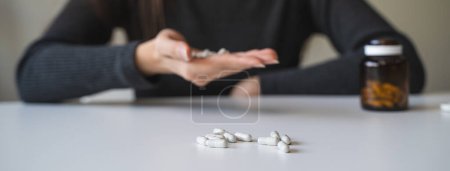 Foto de Cierra las pastillas sobre la mesa. Mujer estresada que toma sobredosis de drogas. - Imagen libre de derechos