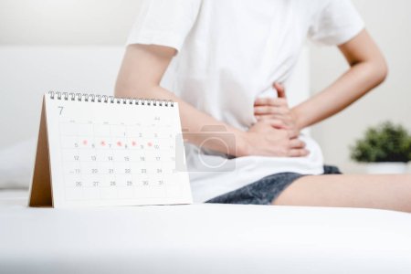 Téléchargez les photos : Menstruation mensuelle symptôme période concept. Fermer calendrier marquage le jour des règles et les femmes ont des douleurs à l'estomac comme arrière-plan. - en image libre de droit