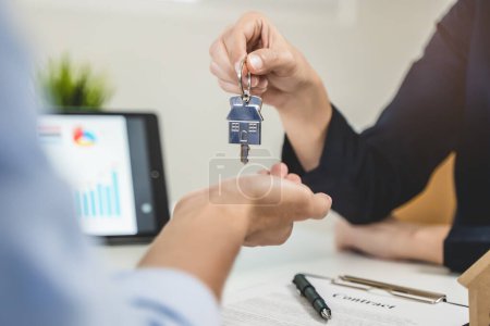 Téléchargez les photos : Realtor agent giving a key of apartment to new owner after signed lease agreement. - en image libre de droit