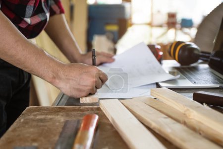 Foto de Hands of person doing diy project at home. Man measuring wood to doing cabinet craftworks as a hobby. - Imagen libre de derechos